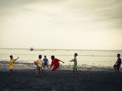 Varios niños juegan al fútbol en la playa.