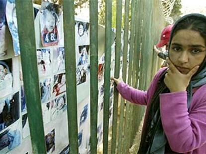 Una mujer repasa un mural con fotografías de las víctimas del terremoto de la semana pasada en Argelia, dispuesto en un cementerio para los familiares reconozcan a los muertos en el seismo.