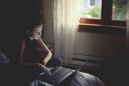 Una niña utiliza un ordenador portátil en su habitación. / GETTY IMAGES