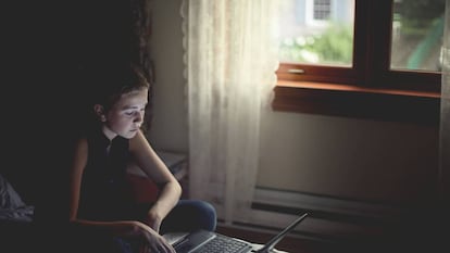 Una niña utiliza un ordenador portátil en su habitación. / GETTY IMAGES