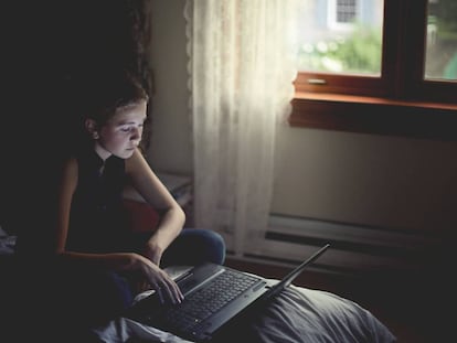 Una niña utiliza un ordenador portátil en su habitación. / GETTY IMAGES