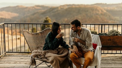 Una pareja hablando con una café caliente en la terraza de su casa.