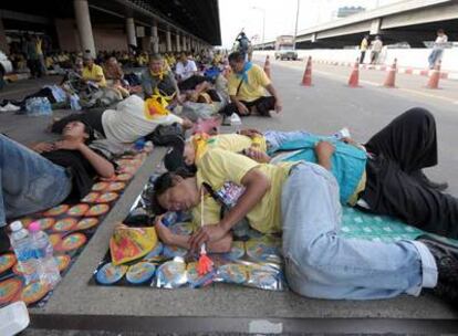 Militantes del APD descansan a las puertas del viejo aeropuerto de Bangkok, donde se ha refugiado el Gobierno tras la toma de la sede del Primer Ministro el pasado agosto
