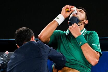 Djokovic toma antiinflamatorios mientras es atendido del costado.