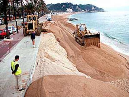 Las excavadoras trasportan la arena de un lado a otro en la playa de Lloret de Mar.