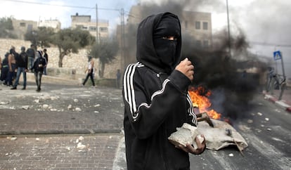 Un manifestante palestino, cerca de neumáticos en llamas, sostiene piedras durante los enfrentamientos con las fuerzas de seguridad israelíes, en Sur Baher (Jerusalén Este).