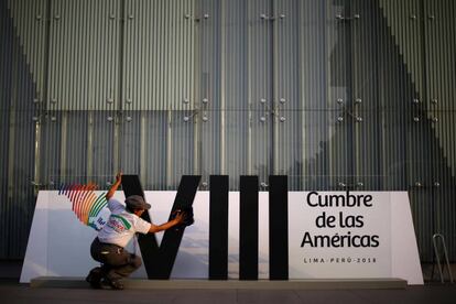 Una mujer limpia el logo de la Cumbre de las Américas en Lima.