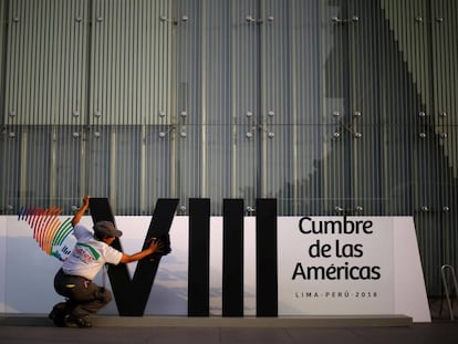 Una mujer limpia el logo de la Cumbre de las Américas en Lima.