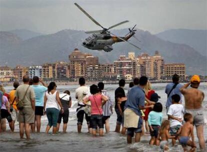 Un grupo de personas contempla la acción de un helicóptero, ayer en la exhibición aérea en la playa de la Malva-rosa de Valencia.