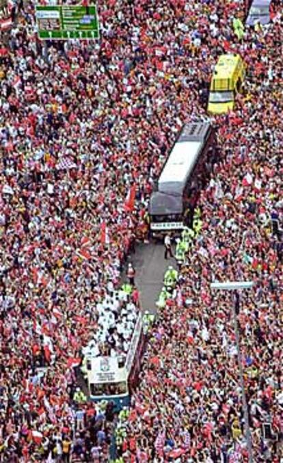 Los jugadores del Liverpool saludan a los aficionados desde un autocar.