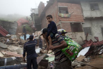 Un hombre y su hijo llevan sus pertenencias tras ser evacuados de una zona con alto riesgo de sufrir un corrimiento de tierra.