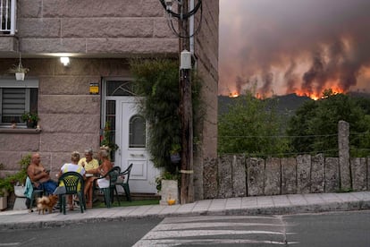 Vecinos de Carballeda de Avia (Ourense) juegan a las cartas mientras avanza el incendio forestal.