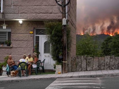 Vecinos de Carballeda de Avia (Ourense) juegan a las cartas mientras avanza el incendio forestal.