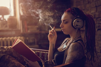 Hipster woman reading a book while listening music on headphones.