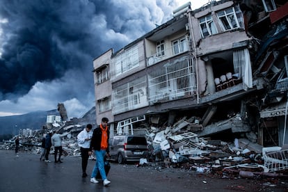 Afectados por el terremoto de Turquía de febrero de 2023 caminan junto a edificios derrumbados en Iskenderun.