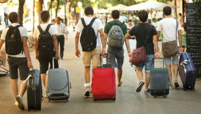 Turistas caminan con sus maletas por la Rambla de Catalu&ntilde;a, en Barcelona.