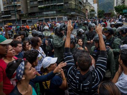 Un grupo de personas manifiestan contra miembros de la Guardia Nacional Bolivariana en Caracas en protesta por la carest&iacute;a.