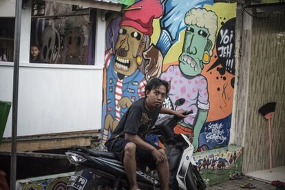 Un vecino del kampung Kedondong, en Surabaya, delante de uno de los murales de X-Go y su equipo.