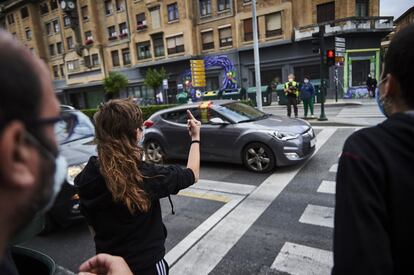 Una mujer increpa a un coche con la bandera de España durante el paso de la caravana convocada por Vox, en Pamplona.