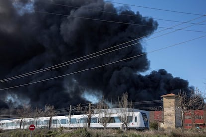 Un convoy de Metrovalencia pasa cerca del incendio del polígono industrial de Paterna momentos después del inicio del siniestro. La línea 2 ha sido suspendida debido al intenso humo originado por el incendio declarado en la empresa química Indukern.