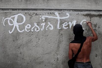 Un activista opositor escribe la palabra 'resistencia' en una pared durante las protestas en Caracas.
