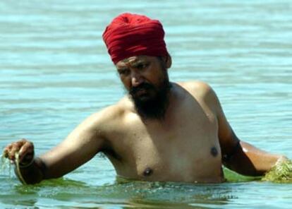 Un trabajador indio limpia a mano el lago de Shinias, antes del entrenamiento de piragüismo.