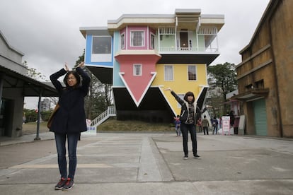 Visitors pose outside of an upside-down house created by a group of Taiwanese architects at the Huashan Creative Park in Taipei, Taiwan, Tuesday, Feb. 23, 2016. With a build price of $600,000 and over 300 square meters (3,230 square feet) of floor space filled with real home furnishings, the upside-down house will continue to be on display to visitors until July 22. (AP Photo/Wally Santana)