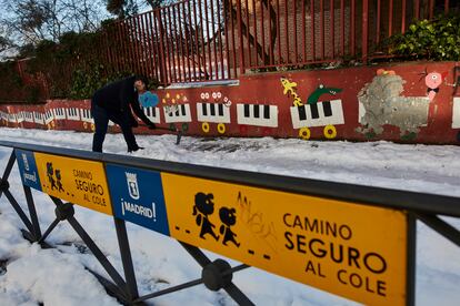 Un familiar colabora en la limpieza del hielo y la nieve en las inmediaciones del colegio Amadeo Vives.
