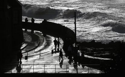 Members of the public watch large waves, produced by storm force winds, break along the coast at Porthleven on October 28, 2013 in Cornwall, England. Approximately 220,000 homes are without power and two deaths have been recorded after much of southern England has been affected by a severe storm.