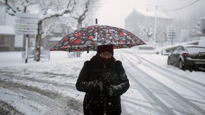 Una mujer se protege de la nieve en Castro Caldelas (Ourense), este miércoles. El 112 ha registrado desde la medianoche del lunes hasta las 6 horas de este miércoles 1.277 incidencias vinculadas al el temporal en Galicia, de las que 160 corresponden a la jornada de hoy.