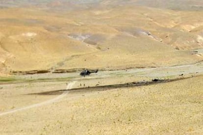 Los restos del aparato siniestrado yacen junto a un río seco en una zona cerca de Herat, en el oeste de Afganistán. A la izquierda, el helicóptero sanitario que acudió al lugar.
