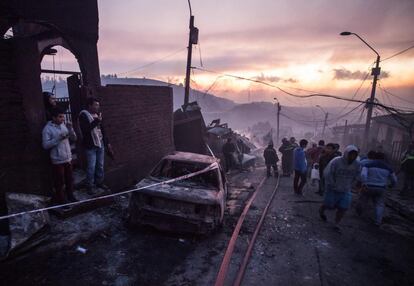 El puerto chileno de Valparaíso, a 120 kilómetros de Santiago y compuesto por 42 cerros, se enfrenta de nuevo a una tragedia a causa de las llamas. En la imagen, un grupo de vecinos observan el estado de las viviendas.