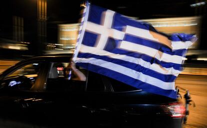 Seguidores griegos portan una bandera de su país a bordo de un coche.