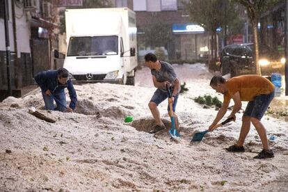 Residents of Arganda del Rey clear the road of hailstones.