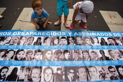 Un grupo de niños mira fotografías de víctimas de la dictadura argentina.