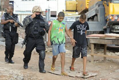 Dos agentes se llevan detenidos a un par de sospechosos en la favela tomada por la policía y el Ejército.