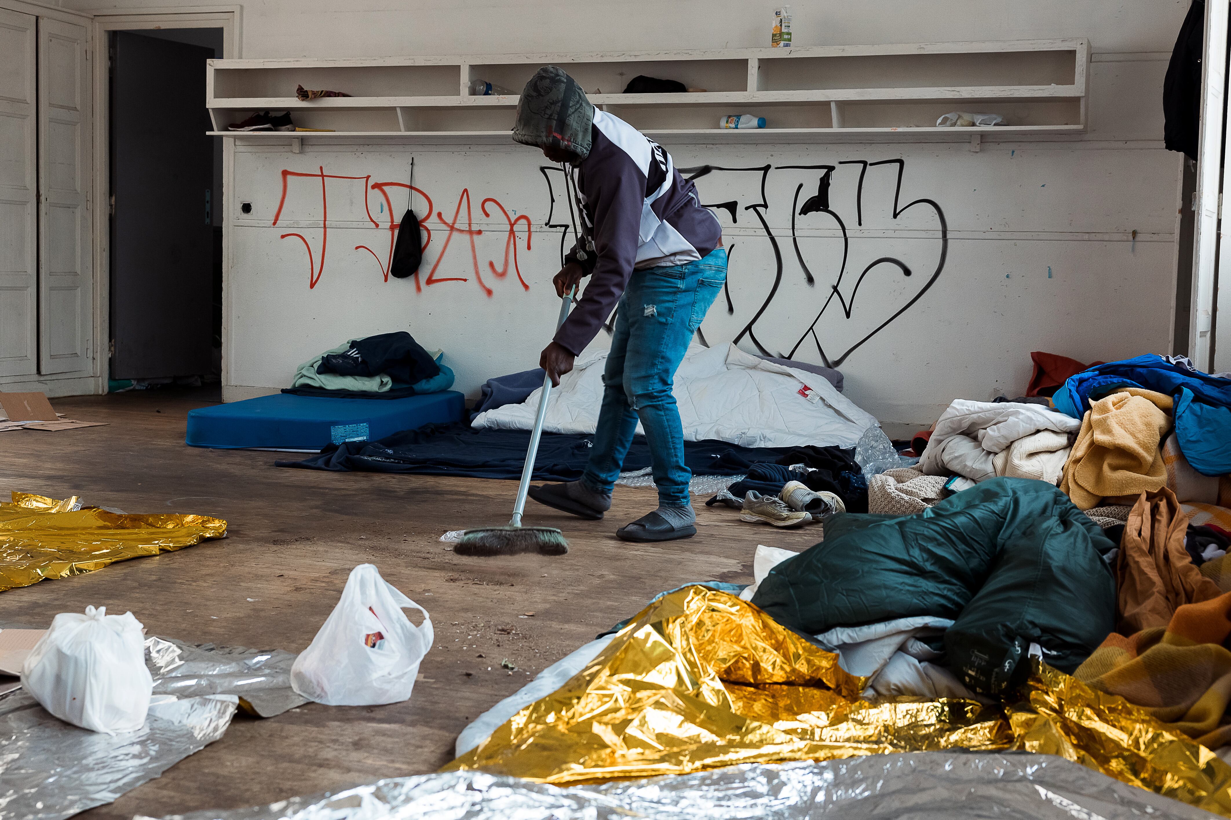 Un residente barre una de las aulas convertidas en dormitorio. 