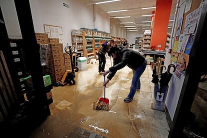 Varios empleados retiran agua y barro del interior de su comercio, este viernes, en la localidad de Villava (Navarra).