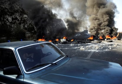 Un hombre duerme en un coche al lado de neumáticos en llamas que bloquean la carretera durante las protestas contra el gobierno Nahr El Kalb (Líbano).