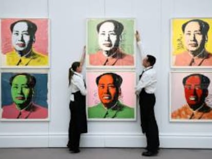 Dos trabajadores colocan varias obras de arte del artista Andy Warhol en las que se retrata al revolucionario comunista chino Mao, en la casa de subastas Sotheby's, Londres, Reino Unido.