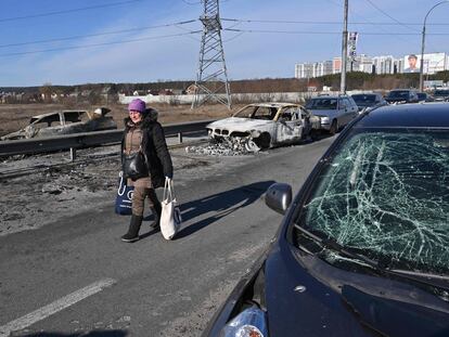 Una mujer camina una zona con coches destrozados en Irpin, al norte de Kiev, la capital ucrania, este sábado 12 de marzo.