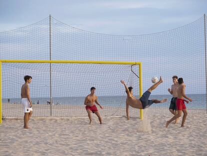 Unos jóvenes juegan al fútbol en la playa de la Victoria en Cádiz, este lunes.