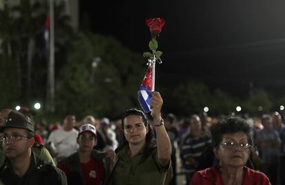 Una mujer muestra una rosa y una bandera cubana durante la ceremonia en honor a Fidel Castro, en Plaza de la Revolución. 