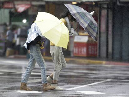 Dos mujeres taiwanesas caminan este viernes bajo la lluvia y los fuertes vientos. 