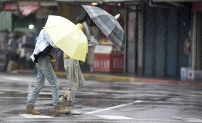 Dos mujeres taiwanesas caminan este viernes bajo la lluvia y los fuertes vientos.