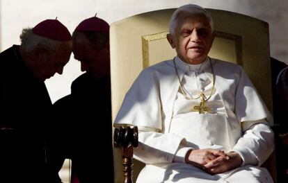 El Papa preside una audiencia en San Pedro mientras dos obispos conversan a su espalda.