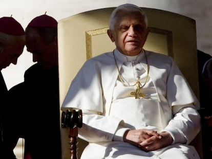 El Papa preside una audiencia en San Pedro mientras dos obispos conversan a su espalda.