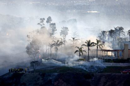 El humo de un incendio forestal que se extiende rápidamente por el viento cubre un área residencial en Laguna Niguel,  California.