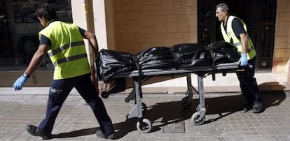 Operarios del retén fúnebre sacan el cuerpo de la mujer fallecida.