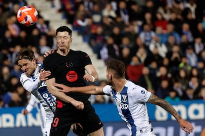 El delantero polaco del Barcelona Robert Lewandowski (c) intenta rematar ante la defensa del Leganés durante el partido de la jornada 31 de LaLiga EA Sports.